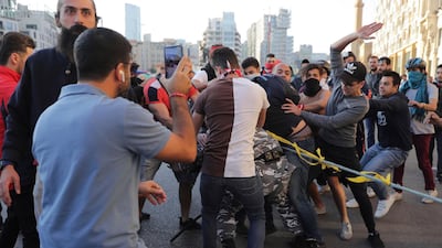 Anti-government protesters hit a police officer as they try to remove barbed wire that blocks a road leading to the parliament building in downtown Beirut. AP Photo