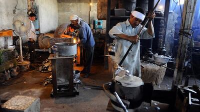 An Afghan labourer, right, pours molten aluminium into a mold at a workshop in Herat.