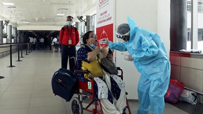 A health worker in personal protective equipment (PPE) collects a swab sample from a woman amidst the spread of the coronavirus disease (COVID-19) at Indira Gandhi International Airport, in New Delhi, India. REUTERS