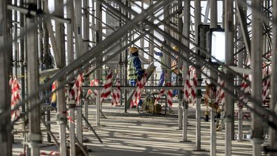 A construction worker is seen through scaffolding.