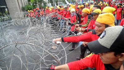 Indonesian workers try to remove a barbed wire fence during a protest against the government in Jakarta. EPA