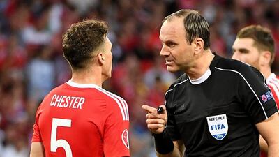 Swedish referee Jonas Eriksson speaks with Wales' defender James Chester during the Euro 2016 group B football match between Russia and Wales at the Stadium Municipal in Toulouse on June 20, 2016. / AFP / PASCAL GUYOT