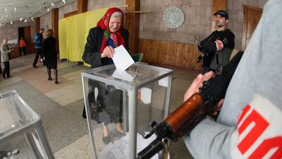 Armed activists stand guard as a woman casts her ballot in Donetsk on May 11, 2014, for the referendum called by pro-Russian rebels on splitting from the rest of Ukraine. Alexander Khudoteply / AFP