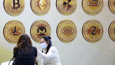 Customers talk against a backboard featuring signs of cryptocurrency during the 2020 Taipei International Finance Expo. Reuters