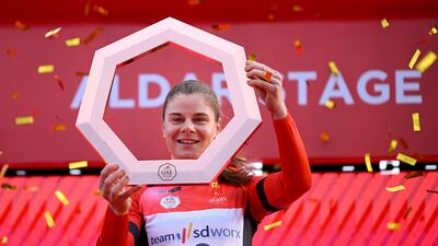 Lotte Kopecky, wearing the race leader's red jersey, celebrates on the podium in Abu Dhabi after after winning the UAE Tour on February 11, 2024. Getty Images