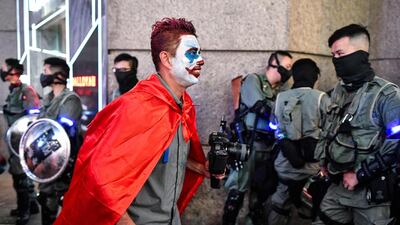 A Halloween reveller walks past a line of policemen in the Lan Kwai Fong area in Hong Kong. Hong Kong democracy protesters are planning to don Halloween masks lampooning the city's pro-Beijing leaders on October 31 evening, defying an emergency law that bans face coverings. AFP