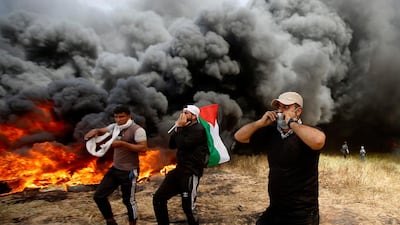 Palestinian protesters chant slogans next to burning tyres east of Khan Younis, Gaza Strip. Adel Hana / AP Photo