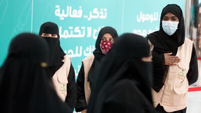 Health workers greet people after they receive their vaccine at a new coronavirus vaccination centre, at the Jeddah old airport in Saudi Arabia. Amr Nabil / AP