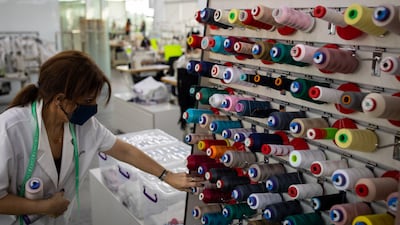 A seamstress looks for thread among the spools on the factory floor.