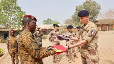Officers from Burkinabe and French forces hold a flag-lowering ceremony to mark the end of operations by the French army in Burkina Faso. AFP.