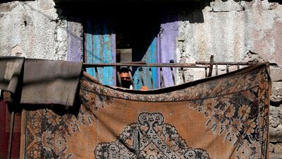 A Palestinian peeks from a balcony in Gaza City. AFP