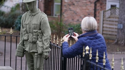A passer-by looks at a life-sized knitted soldier that has been placed at the War Memorial Clock Tower in Syston, Leicestershire, by an anonymous knitter known only as Knitting Banksy. PA