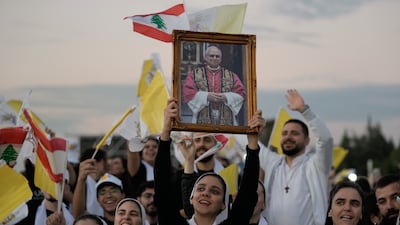 People hold aloft a portrait of Pope Leo as an expectant crowd awaits his arrival in Bkerki. AP