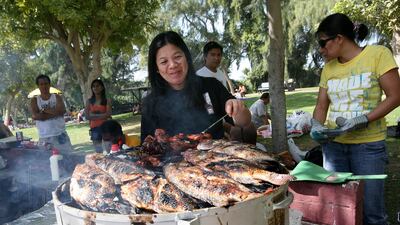 Adela Vellanueve cooks fish and chicken at Safa Park. Beaches and parks around Dubai started filling up early as thousand of residents enjoy the extended Eid break. Mike Young / The National
