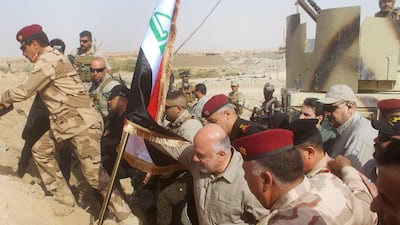 Iraqi prime minister Haider Al Abadi prepares to erect a national flag at a Syria border crossing near Qaim on November 5, 2017, after it was retaken from ISIL by Iraqi troops. Moadh Al Dulaimi / AFP