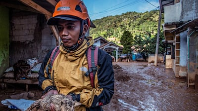 A rescuer holds a cat after a flash flood triggered by heavy rains in Purasari village in Bogor, Indonesia. AFP