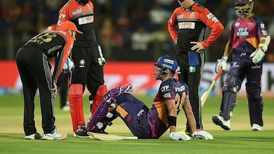Rising Pune Supergiants batsman Kevin Pietersen sits on a ground after getting injured while batting as Royal Challengers Bangalore player AB de Villiers (2nd R) and captain Virat Kohli (L) speak during the 2016 Indian Premier League (IPL) Twenty20 cricket match between Royal Challengers Bangalore and Rising Pune Supergiants at The MCA International Cricket Stadium in Pune on April 22, 2016. Punit Paranjpe / AFP