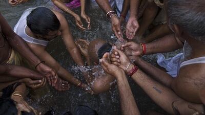 Hindu devotees bath a sadhu, or Hindu holy man, center, in the Godavari River during Kumbh Mela, or Pitcher Festival in Nashik, India, Saturday, Aug. 29, 2015. Hindus believe taking a dip in the waters of a holy river during the festival will cleanse them of their sins. Tsering Topgyal / AP