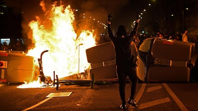 A protester gestures in front of trash containers in flames during clashes with Catalan regional police forces. AFP