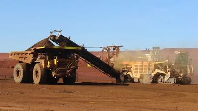 An earth mover receives a load of iron ore from a surface miner in the mine pit at Fortescue Metals Group's Cloudbreak operation in the Pilbara region of Western Australia.