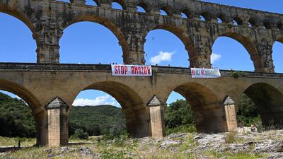 Activists from Attac France stands on the Pont du Gard near two banners reading 'Stop Amazon' and 'Neither here nor elsewhere'. AFP