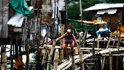 A villager crosses a makeshift bridge at a coastal village near Bacoor city, in Cavite province, about 30km south-east of Manila. Scores of people are dead or missing in the Philippines due to floods and landslides caused by the passage of three tropical storms. EPA