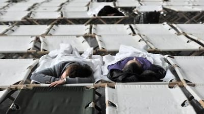 Passengers sleep on camp beds at Frankfurt airport in Germany after snow and icy conditions led to the cancellation of flights.