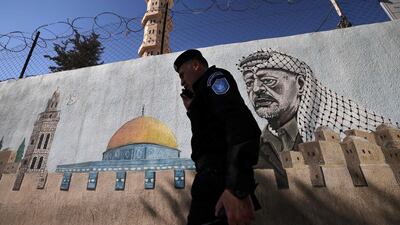 A Palestinian Authority policeman walks outside a police station adorned with a painting depicting late Palestinian leader Yasser Arafat, in the West Bank city of Hebron, earlier this month. AFP