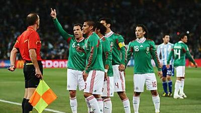 Mexico players swarm referees after an offside goal by Carlos Tevez.