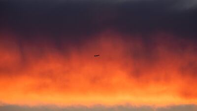 An plane flies past a cloud band illuminated by the setting sun in Frankfurt, western Germany. AFP