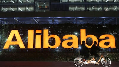 People ride a double bicycle past a logo of The Alibaba Group at the company's headquarters on the outskirts of Hangzhou, Zhejiang province on November 10, 2014. Aly Song / Reuters