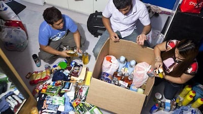 John Paul, 27, Francis, 28, and Angel Laguilles, 25, prepare a balikbayan box to send to their family in the Philippines.