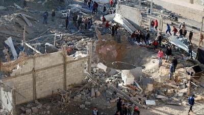 Palestinians gather around a militant target that was hit in an Israeli airstrike. Mohammed Salem / Reuters
