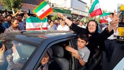 Iranian football fans wave their national flag and flash the victory sign during celebrations in Vanak square in northern Tehran.