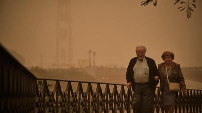 A couple walk across a bridge in a cloud of red dust in Santa Cruz de Tenerife, Spain. AP Photo