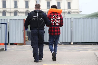 A migrant is escorted by a Border Force officer after trying to cross the English Channel in a small boat. AP