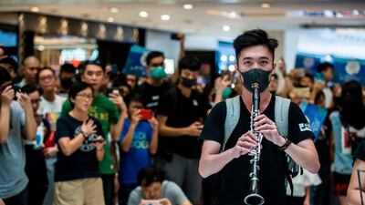 A man plays the clarinet as people sing at an anti-government rally inside a shopping mall at the Sha Tin district of Hong Kong. AFP
