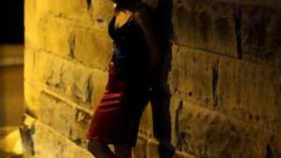 A Sex worker peers down a street in Sydney.