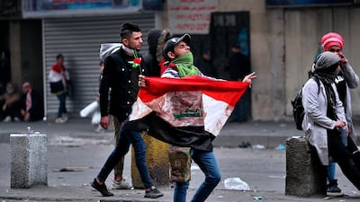 A protester holds an Iraqi flag during clashes between security forces and anti-government protesters in central Baghdad. AP Photo