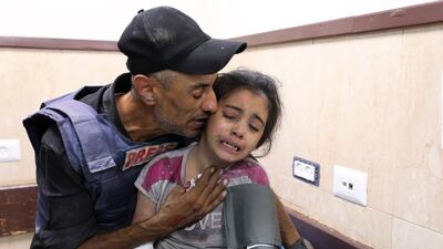 A Palestinian journalist comforts his niece after she was wounded in an Israeli strike on Nuseirat refugee camp. AP