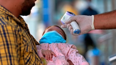 Customers of a convenience store have their temperature checked and are given gloves before they are allowed to enter in Baghdad, Iraq. AP Photo