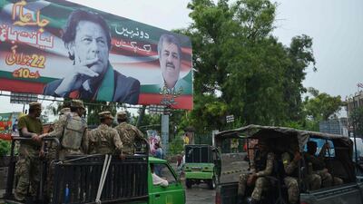 Pakistani soldiers patrol on a street beside a billboard featuring an image of Pakistani cricketer turned politician Imran Khan (top L) of the Pakistan Tehreek-e-Insaf (Movement for Justice), ahead of general election in Rawalpindi on July 23, 2018. AFP