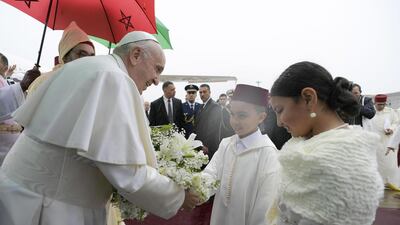 Pope Francis receives flowers from children upon arriving at the airport. EPA