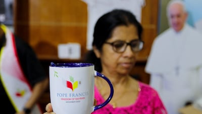 A vendor shows a coffee mug made to celebrate Pope Francis's visit, at a souvenir stand at Sacred Heart Catholic Church in Manama.