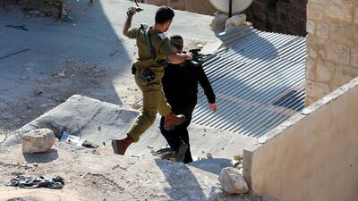 Israeli soldiers and settlers stand over a Palestinian house near the Ibrahimi mosque, also known as cave of patriarchs, in the West Bank city of Hebron. EPA