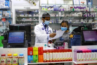 Pharmacists behind a counter covered by glass, during the 24 hour lockdown in Dubai. Reutetrs