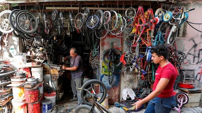 A Palestinian boy waits on a bicycle repair man outside his store in the Amari refugee camp near the West Bank city of Ramallah. AFP