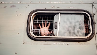 A supporter of the opposition Movement for Democratic Change (MDC) Alliance gestures the party's symbol from inside of a prison truck following an appearance at the magistrate's court in Harare, on August 6, 2018 after many MDC supporters were arrested in post election violence. Zinyange Auntony / AFP