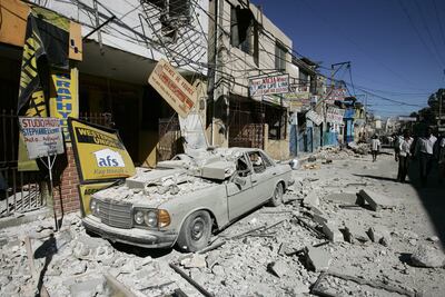 People walk next to debris on a street of the downtown in Puerto Principe, Haiti, 13 January 2010, after a 7.0 magnitude earthquake struck. EPA