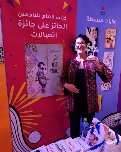 Taghreed standing in front of the Etisalat Banner with her award. Courtesy Taghreed Najjar